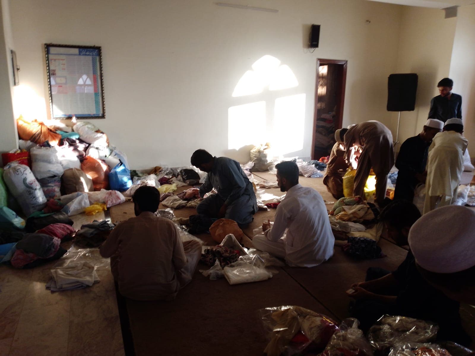 Volunteers sorting donated clothes and relief bundles in a hall