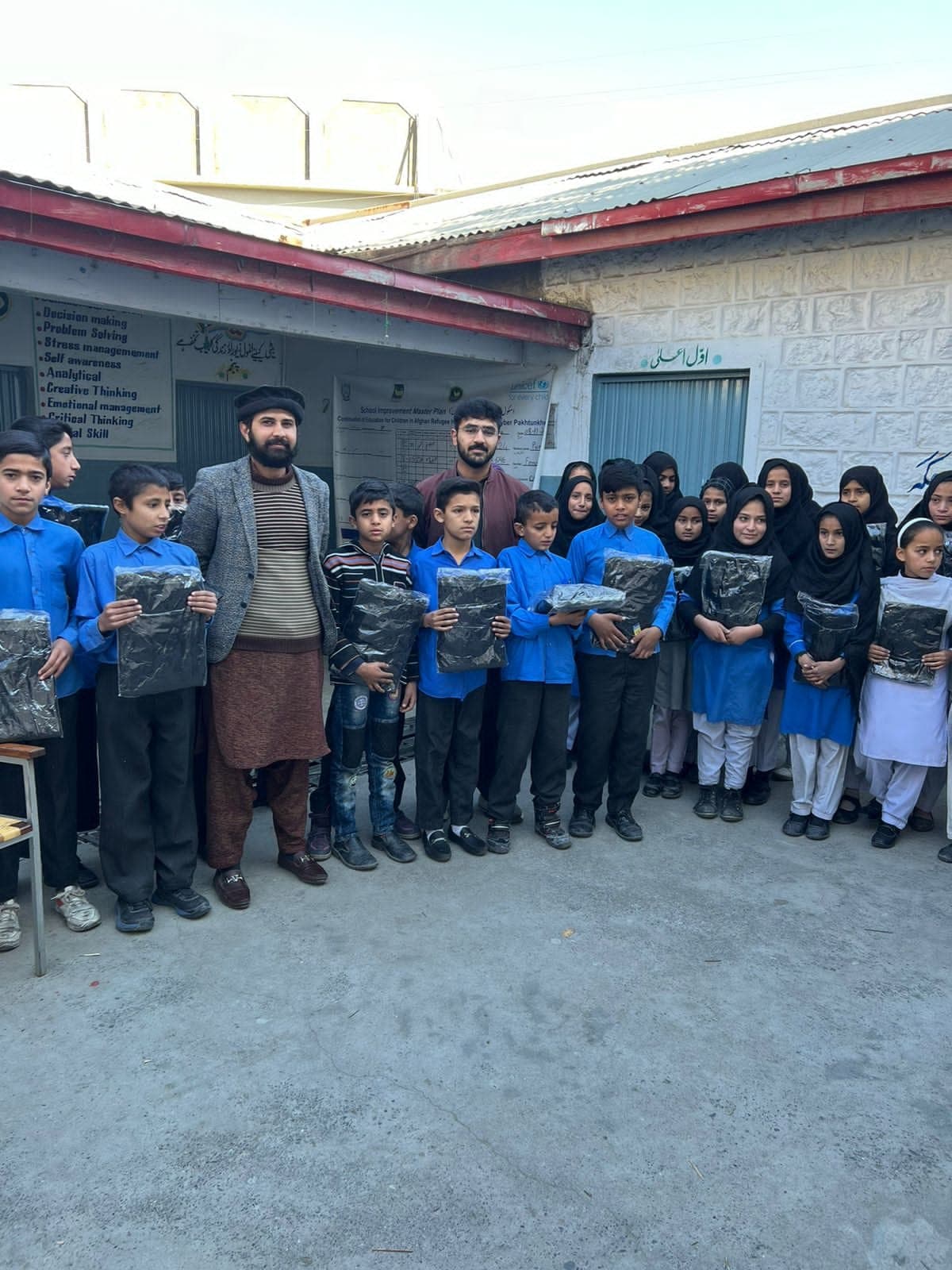 Schoolchildren holding the warm sweaters we handed out in winter