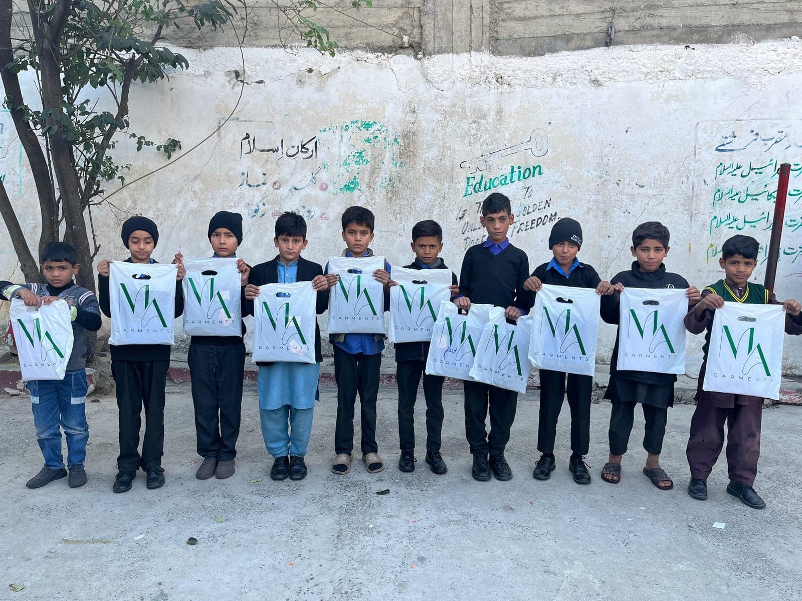 Boys holding their new uniform bags in the school yard, December 2024