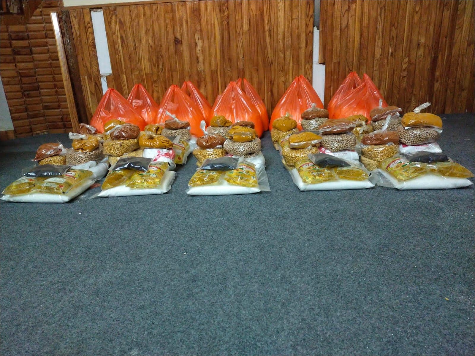 Rows of monthly ration packs: flour, pulses, oil and spices, packed for each family